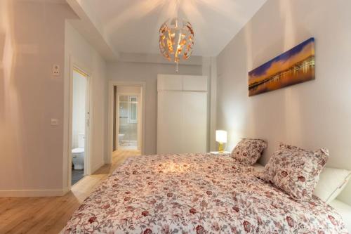 um quarto com uma cama grande e um lustre em Apartamento Miribilla em Bilbao