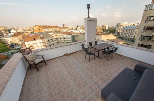 a patio with a table and chairs on a balcony at Color Apartments Nicolae Tonitza St in Bucharest