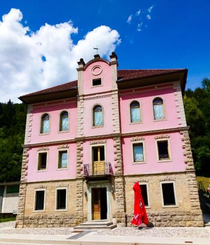 a pink building with a clock tower on top of it at La casa del popolo in Prato Carnico