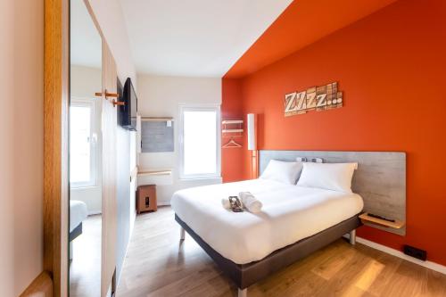 Cama en habitación con pared de color naranja en Ibis Budget Bilbao City, en Bilbao