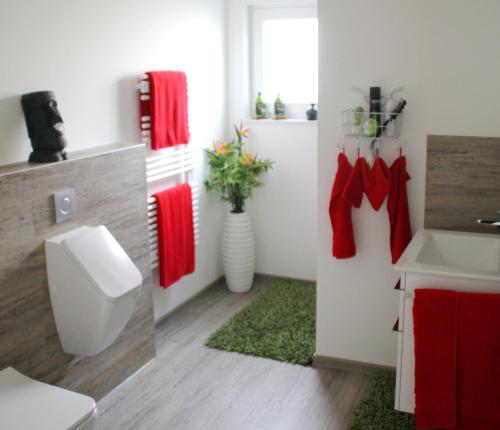 y baño con aseo, lavabo y toallas rojas. en REBENBLÄTTLE, en Bad Dürkheim
