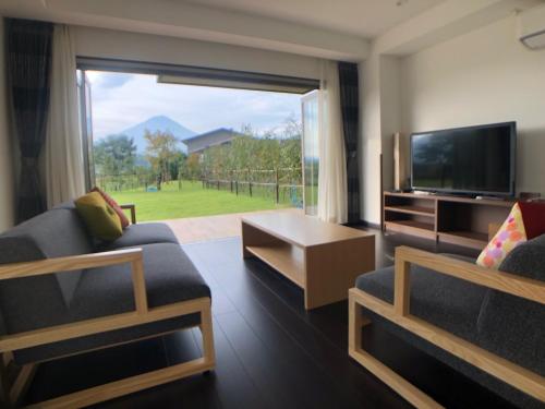 a living room with a large window and a television at Kawaguchiko Urban Resort Villa in Fujikawaguchiko