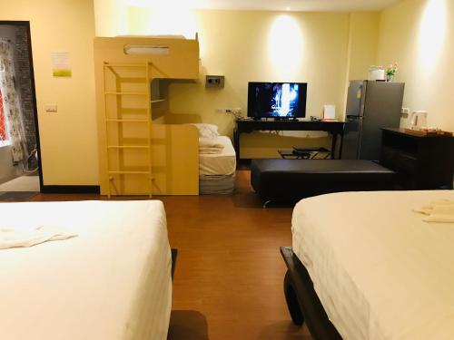 a room with two beds and a desk and a television at Baan Sang Singh in Chiang Mai