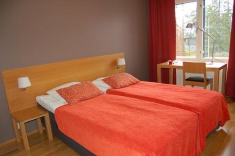 a bedroom with a red bed with a desk and a window at Ruka Chalets 1201 in Ruka