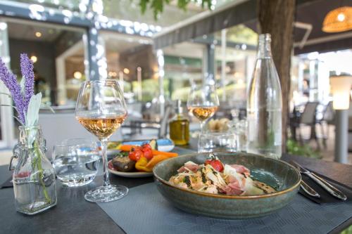 a table with a bowl of food and glasses of wine at Mercure Cavaillon in Cavaillon