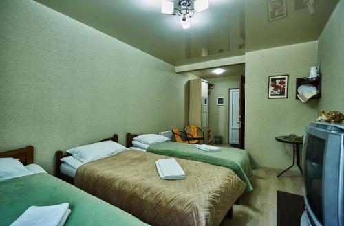 a hotel room with two beds and a tv at Domashniy in Kamianets-Podilskyi