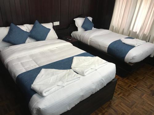two beds in a hotel room with blue pillows at Hotel Green Horizon in Kathmandu