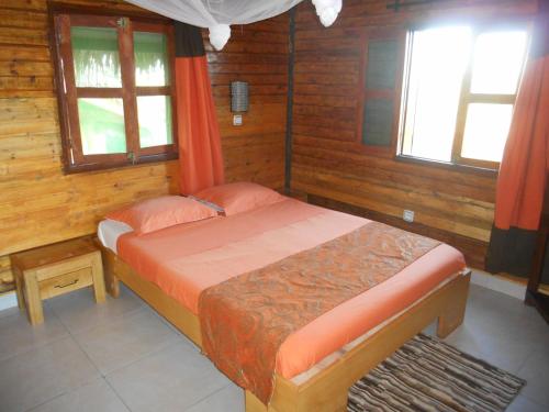 a small bedroom with a bed and two windows at hotel trecicogne in Morondava