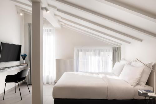 - une chambre blanche avec un lit et une télévision dans l'établissement Thess Residences, à Thessalonique