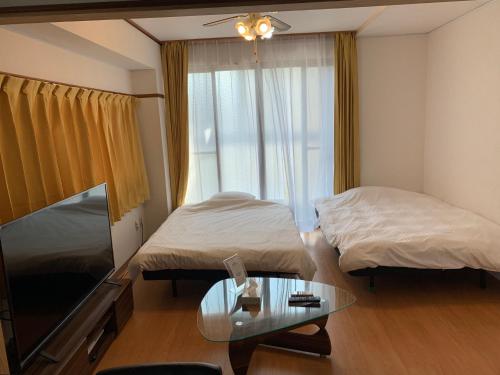 una camera d'albergo con due letti e un tavolo in vetro di ガナダン中央駅 2f 無料駐車場 a Kagoshima