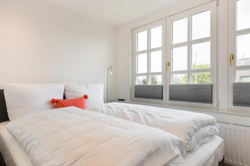 a white bedroom with a large white bed with windows at Oma Lieschen in Keitum