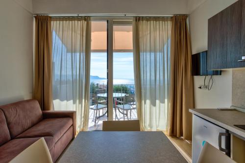 a living room with a couch and a kitchen with a balcony at La Chioma di Berenice Garda Residence in Toscolano Maderno