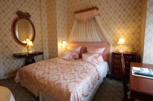a bedroom with a bed and a dresser and a mirror at Hvedholm Slotshotel in Fåborg