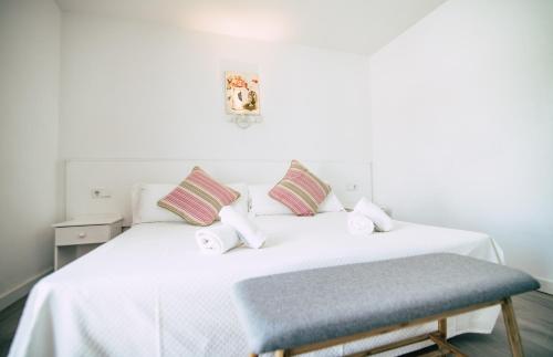 a bedroom with a white bed with a blue stool at Hostal La Llagosta in Llafranc