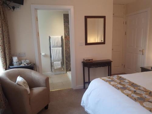 a bedroom with a bed and a chair and a mirror at Berry House Bed & Breakfast in Littlehampton