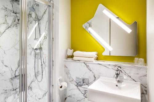 
a bathroom with a sink, mirror and bath tub at ibis budget Luton Airport in Luton
