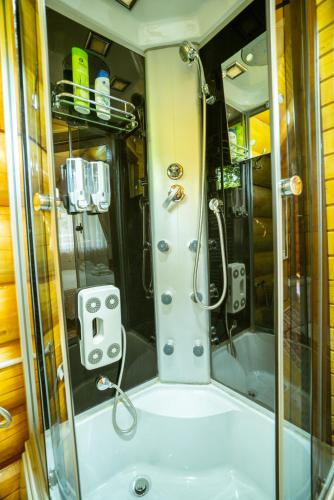 a shower with a glass door in a bathroom at Casutele Din Moisei in Moisei