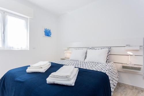a white bedroom with a blue bed with towels on it at Sleep Inn Lagos - Rooms in Lagos