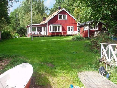 a red house with a boat in front of it at 4 star holiday home in SOLLENTUNA in Sollentuna