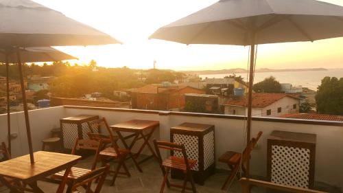 a balcony with tables and chairs and an umbrella at La Estacion Hostel - Pipa in Pipa
