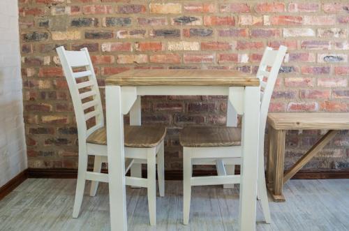 a wooden table with two chairs and a brick wall at Opstal Guestfarm in Potchefstroom