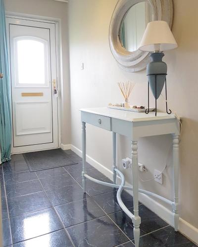 a white table with a lamp and a mirror at Ula Cottage in Saint Helens
