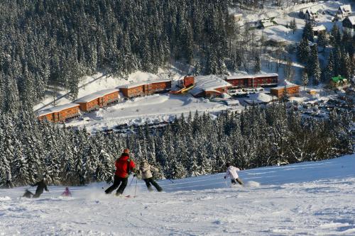 a group of people skiing down a snow covered slope at Resort Špindl in Špindlerův Mlýn