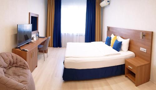 コヴロフにあるOLIMPIA DeLuxeのベッド、デスク、テレビが備わるホテルルームです。