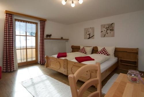 Un dormitorio con una gran cama de madera con almohadas rojas en Weißenbach´s Ferienhof, en Wertach