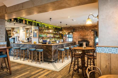 a bar with wooden stools and a brick wall at The Potting Shed Maidstone in Langley