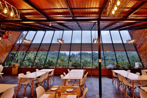 a restaurant with tables and chairs and a large window at Le Villagio Resort & Domes in Sultan Bathery