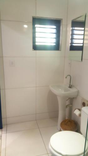 a white bathroom with a toilet and a sink at La Estacion Hostel - Pipa in Pipa
