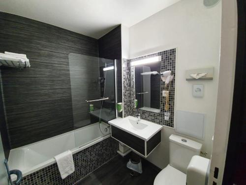 La salle de bains est pourvue d'un lavabo, de toilettes et d'une baignoire. dans l'établissement Kyriad Saint Fargeau Ponthierry - Apollonia, à Saint-Fargeau-Ponthierry