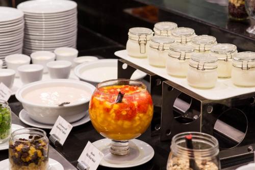 a table with glasses of fruit and jars of food at Mida Grande Hotel Dhavaravati Nakhon Pathom - SHA PLUS in Nakhon Pathom