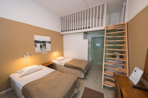 Habitación pequeña con 2 camas y escalera. en Hyvärilä Youth- and Holiday Centre, en Nurmes