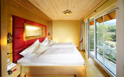 a bedroom with a bed with a red headboard and a window at Hotel Rebstock Durbach in Durbach