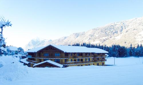 une cabane en rondins dans la neige avec des montagnes en arrière-plan dans l'établissement Vacancéole - Résidence Grand Massif, à Morillon