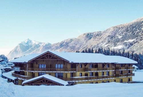 un bâtiment recouvert de neige avec des montagnes en arrière-plan dans l'établissement Vacancéole - Résidence Grand Massif, à Morillon
