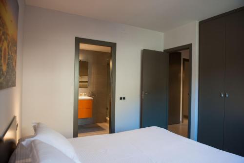 a bedroom with a white bed and a bathroom at WinTuWin Apartments in Rialp
