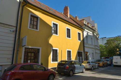 a yellow building with cars parked on a street at BlueBell Hotel in Bratislava