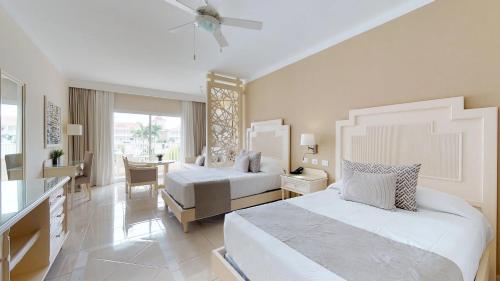 a hotel room with two beds and a desk at Bahia Principe Fantasia Punta Cana - All Inclusive in Punta Cana