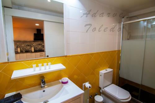 a bathroom with a sink and a toilet and a mirror at Apartamentos Adarve Toledo in Toledo