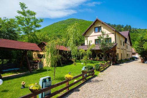 una casa con una valla y una montaña en el fondo en Pensiunea Domnescu, en Sălişte