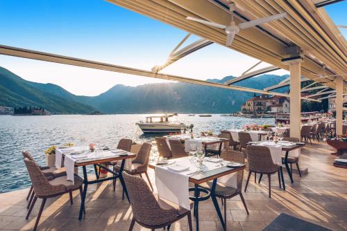 a restaurant on the water with tables and chairs at Heritage Grand Perast By Rixos in Perast