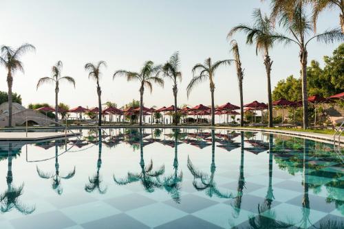 a large swimming pool with palm trees in the background at Esperos Palace Resort in Faliraki