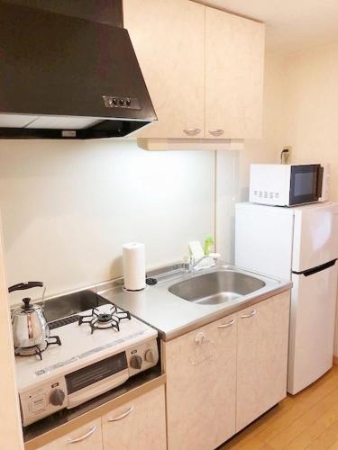 a kitchen with a stove and a sink and a refrigerator at ピオーレ大手門401 in Fukuoka