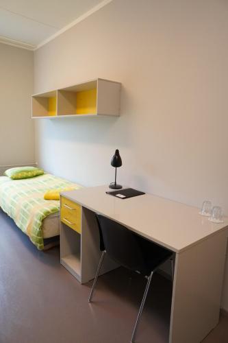 einen Schreibtisch in einem Zimmer mit einem Bett und einem Schreibtisch mit einer Lampe in der Unterkunft Downtown Hostel in Tartu