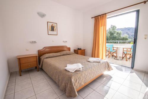 1 Schlafzimmer mit einem Bett und einem Balkon mit einem Tisch in der Unterkunft Angelika Apartotel in Mílatos