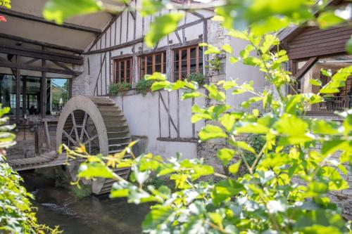 an old house with a waterwheel in front of it at Le Moulin Du Landion Hôtel et Spa in Dolancourt