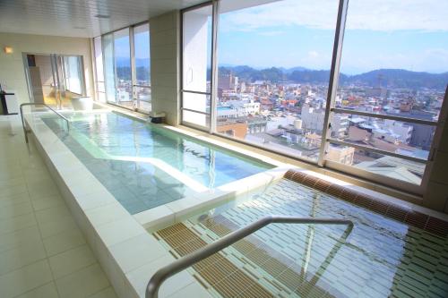 a swimming pool in a building with a view of a city at Spa Hotel Alpina Hida Takayama in Takayama